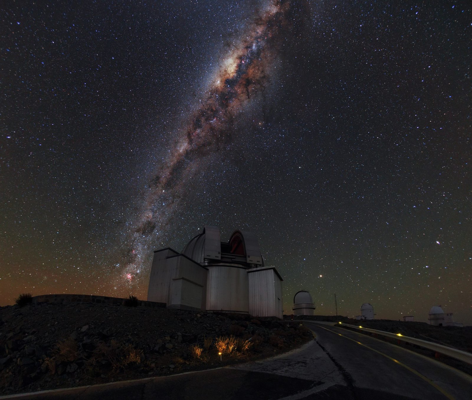 The bright band of the Milky Way rising above observatory domes at La Silla in Chile