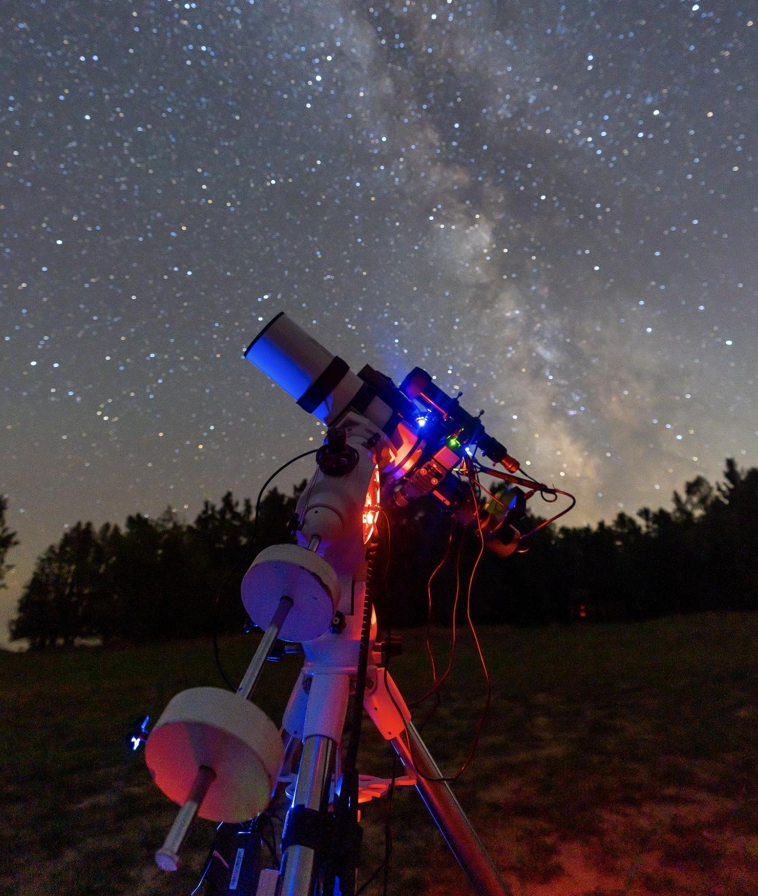 A telescope on an equatorial mount, tracking under a starry sky with the Milky Way visible